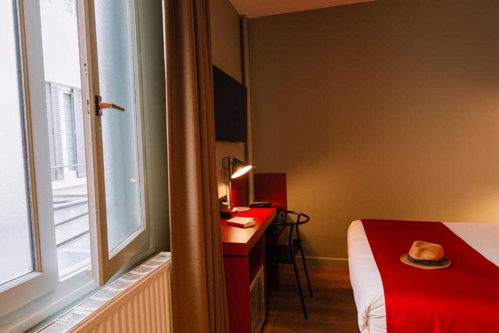 a room with a bed and a desk and a window at Hôtel de Noailles in Lyon