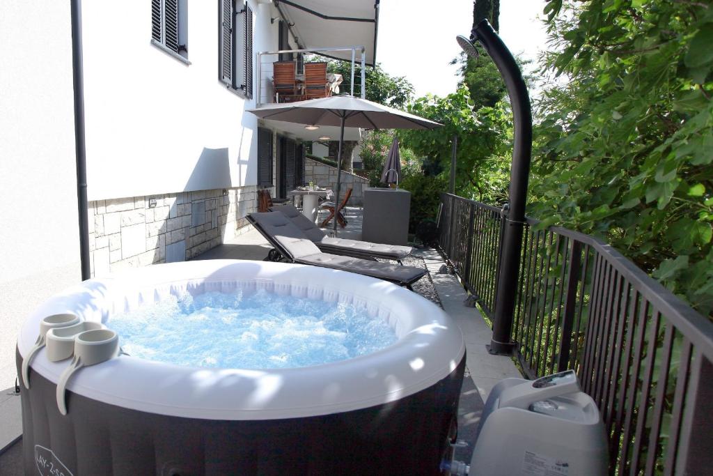 a jacuzzi tub on a balcony with an umbrella at Modern Apartment Parenzana IZMA in Portorož