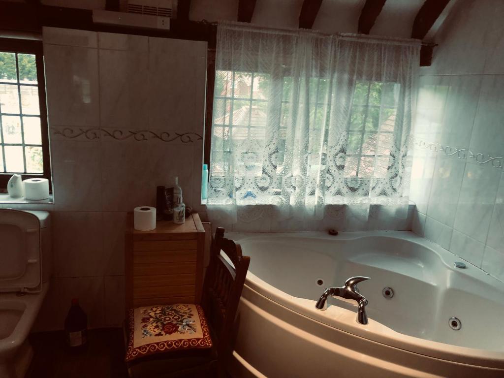 a bathroom with a tub and a window and a sink at Tudor House - Double Room - Shared Bathroom in Goffs Oak