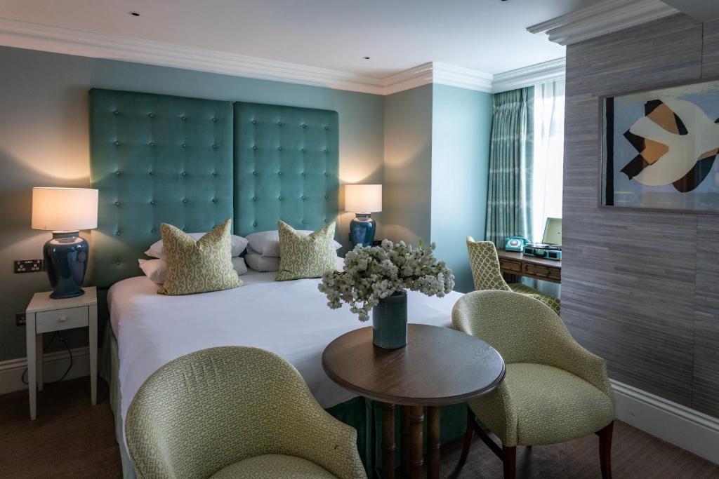 a bedroom with a large bed with chairs and a table at Roslin Beach Hotel in Southend-on-Sea