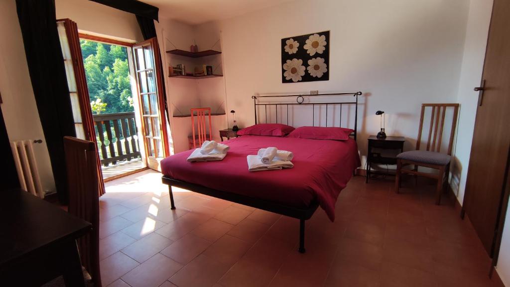 a bedroom with a red bed and a balcony at Hotel Edelweiss in Bognanco