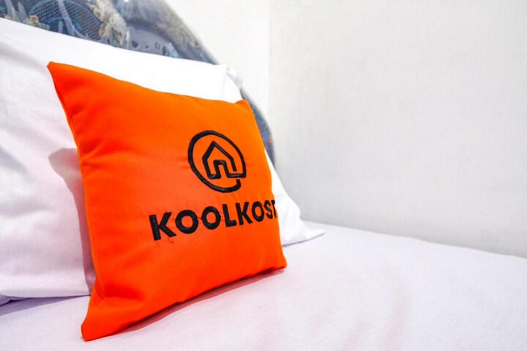 an orange pillow sitting on top of a bed at KoolKost Syariah @ Dukuh Kupang (Minimum Stay 30 Nights) in Putat-wetan