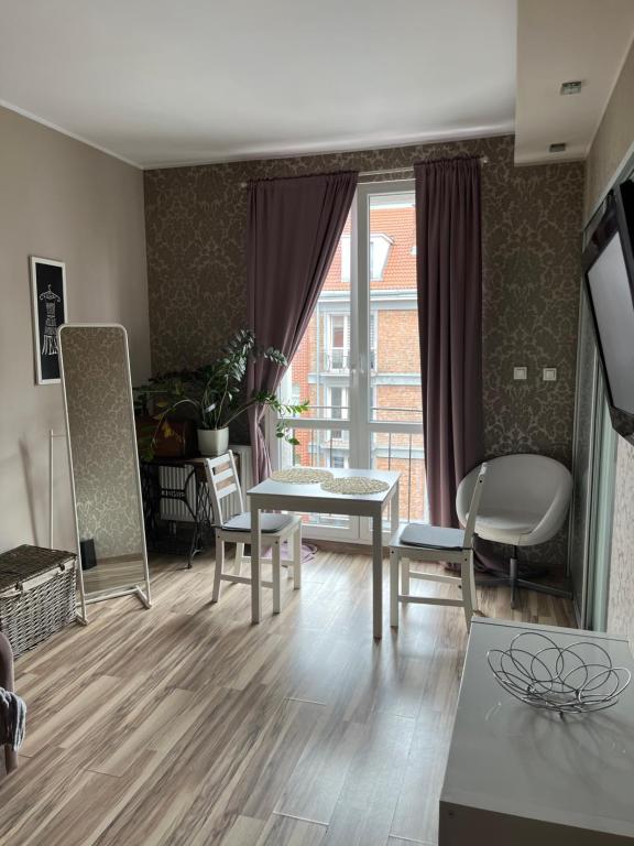 ein Wohnzimmer mit einem Tisch, Stühlen und einem Fenster in der Unterkunft Centrum Apartament in Danzig