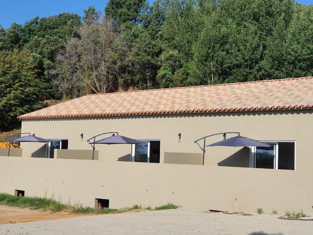 a white building with blue umbrellas on it at Casa di lise e bastien in San-Nicolao