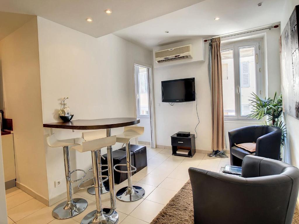 un salon avec une table, des chaises et une télévision dans l'établissement 1 Bedroom Notre Dame 2 mins from the Croisette and the Palais 225, à Cannes