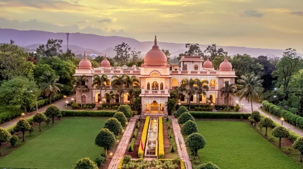 una imagen de un palacio con jardín y árboles en WelcomHeritage Shivavilas Palace, HAMPI en Hospet