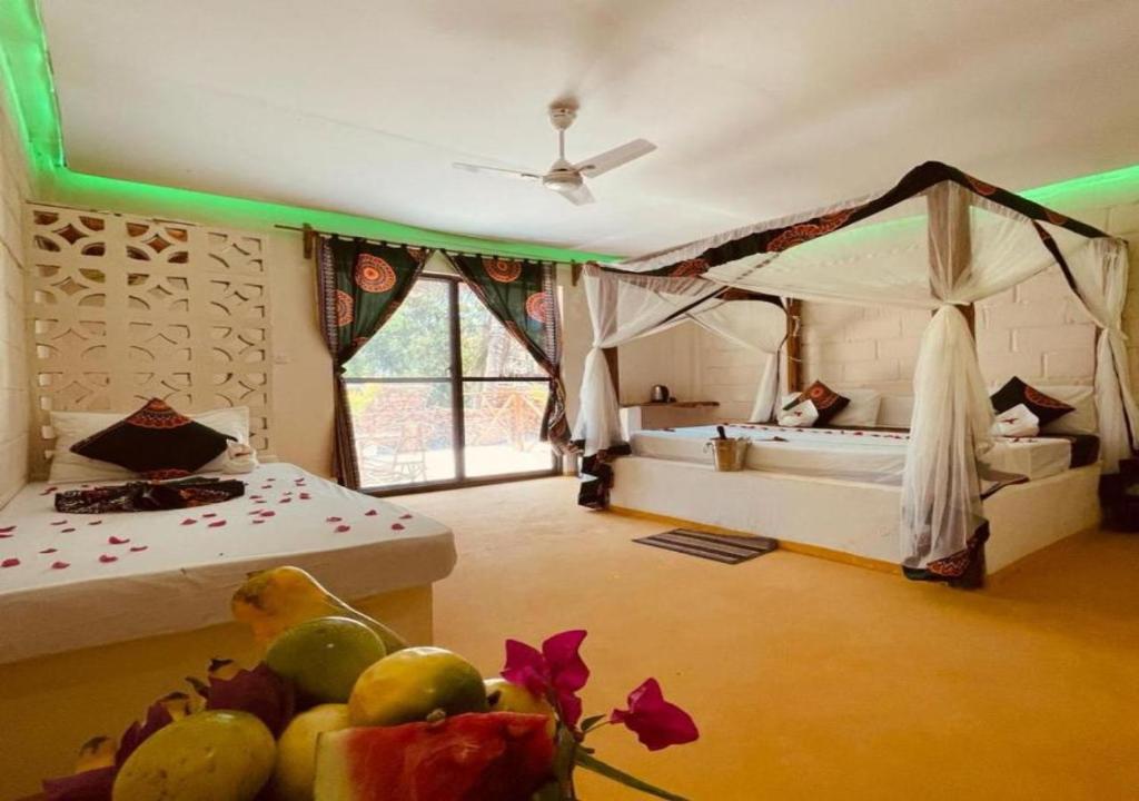 a room with a bedroom with two beds and a table with fruit at Tropicana Garden in Kendwa