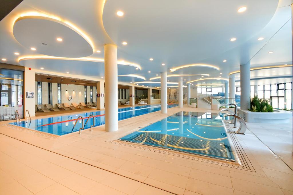 a large swimming pool in a large building with a pool at Klif Apartamenty Polanki Aqua in Kołobrzeg