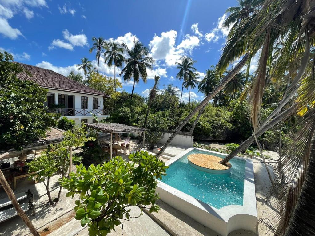 an image of a villa with a swimming pool and palm trees at KIMA Serviced Beach House & Suites in Bwejuu