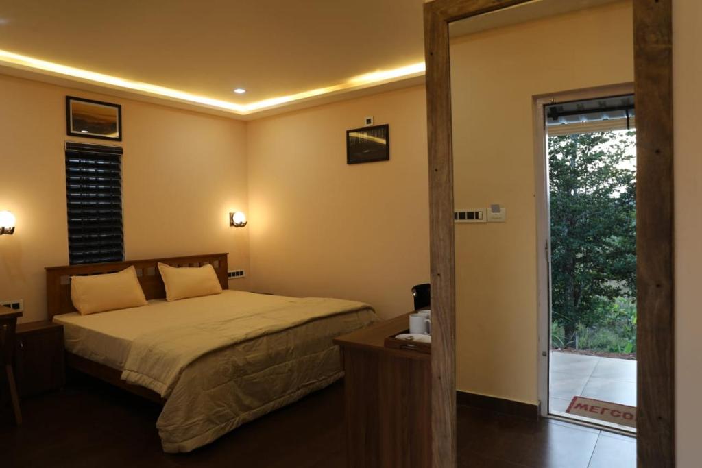 - une chambre avec un lit et une porte coulissante en verre dans l'établissement Agronest Farm by LivingStone, à Sultan Bathery