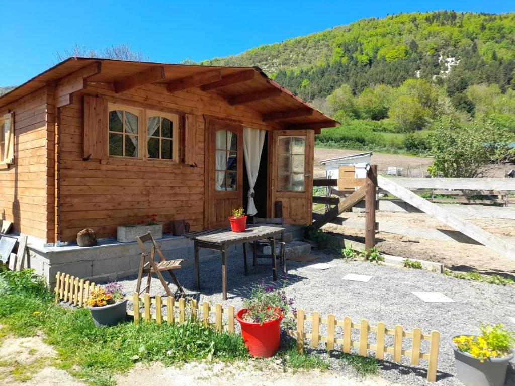 Cabaña de madera pequeña con mesa y valla en Le Ranch du Madres, en Roquefort-de-Sault