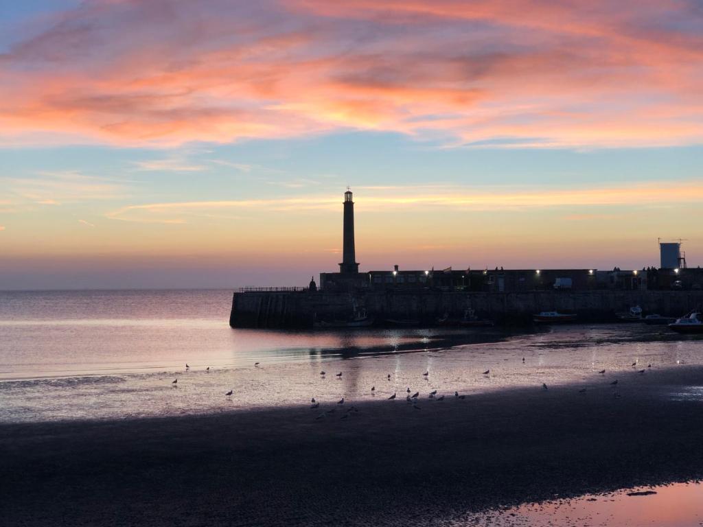 a lighthouse on the beach with birds on the sand at The Beetroot in Margate