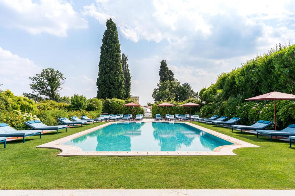 a large swimming pool with chairs and umbrellas at Byblos Art Hotel Villa Amistà in San Pietro in Cariano