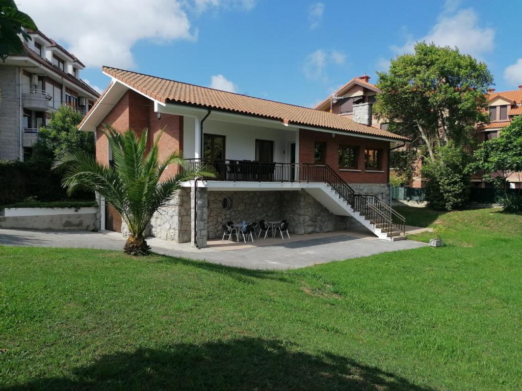 une maison avec un balcon et une pelouse dans l'établissement Villa El Encinar de Noja, à Noja