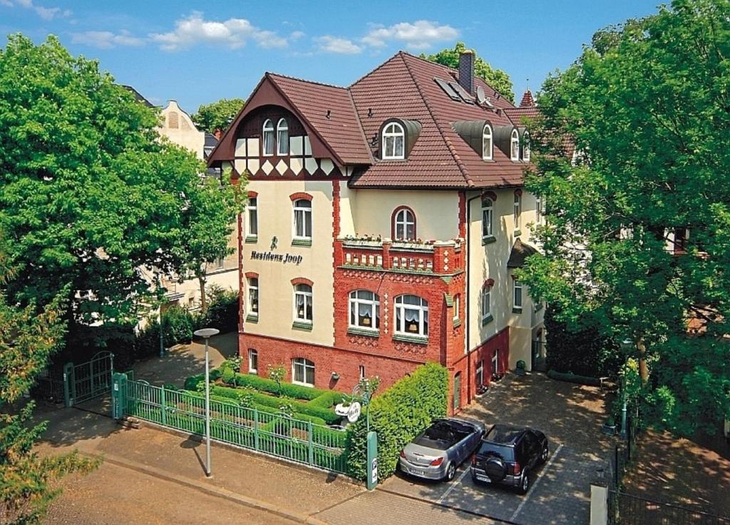 a large house with two cars parked in front of it at Hotel Residenz Joop in Magdeburg