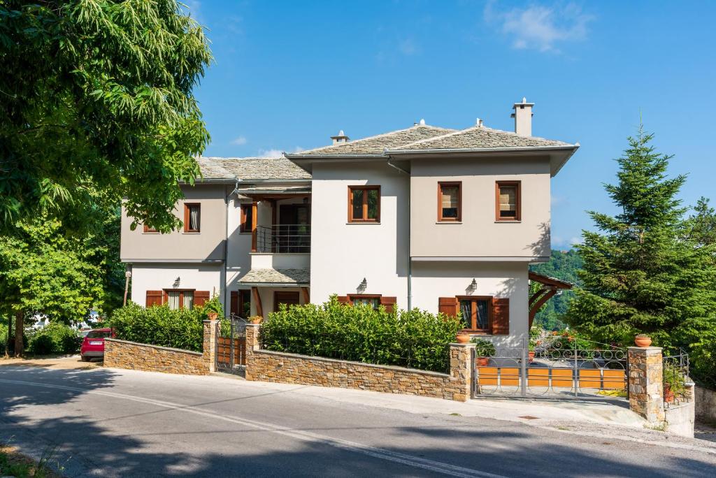 a white house with a fence in front of a street at Άλυσσος suites in Tsagarada