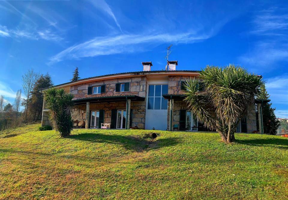 une grande maison sur une colline avec des palmiers en face de celle-ci dans l'établissement Quinta do Casarão by VinteOito - Casa de Campo com Piscina, à Amarante