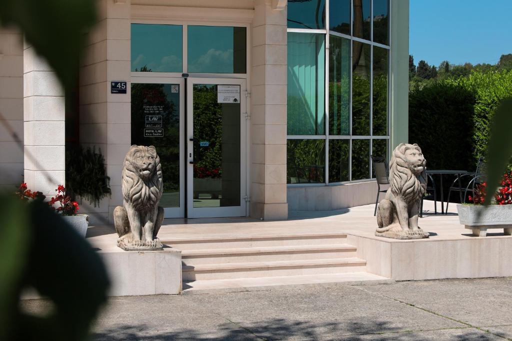 two statues of lions in front of a building at Motel Lav in Čapljina