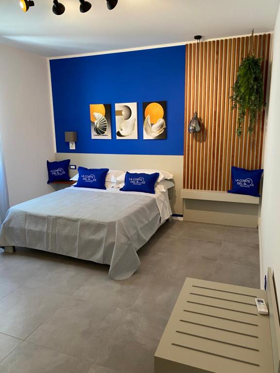 1 dormitorio con paredes azules y 1 cama con almohadas azules en La Corte del Sole en Vieste