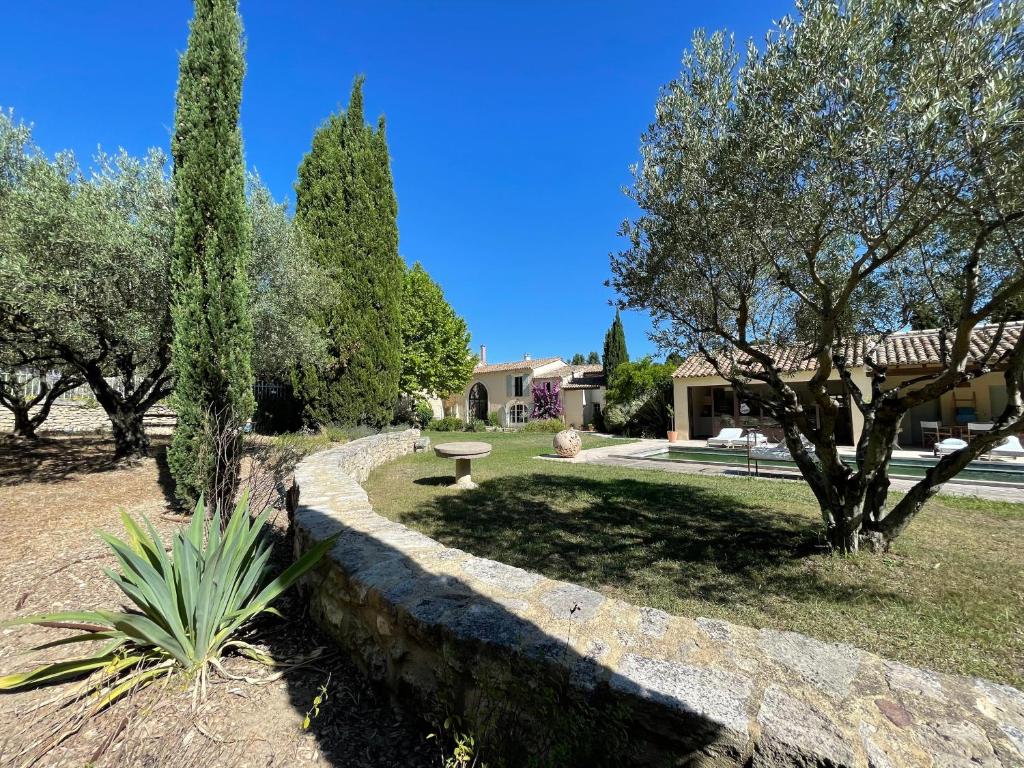 a garden with trees and a stone wall at MAS MILLÉSIME - Chambre double - petit déjeuner - piscine - Mas du XVIIIème siècle proche Saint-Rémy-de-Provence in Mas blanc des Alpilles