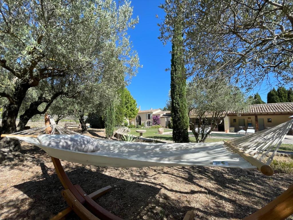 a hammock in a yard with trees and a house at MAS MILLÉSIME - Chambre double - petit déjeuner - piscine - Mas du XVIIIème siècle proche Saint-Rémy-de-Provence in Mas blanc des Alpilles