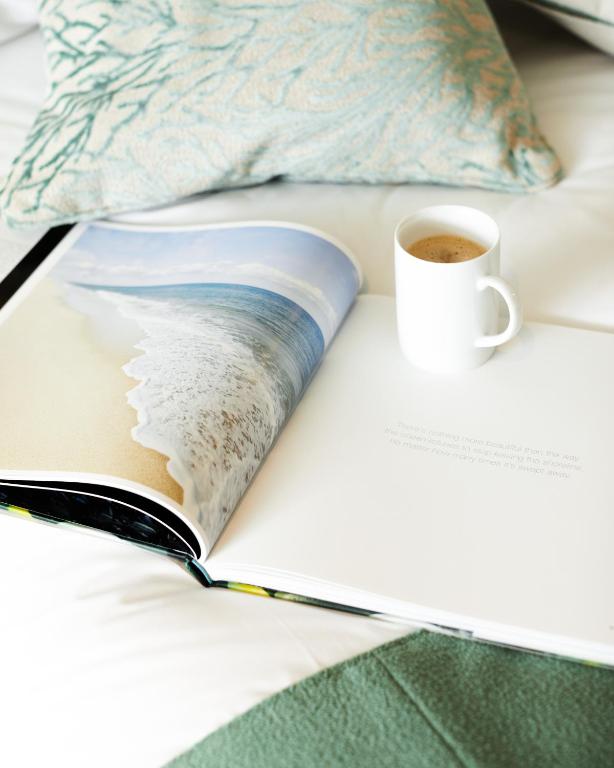 an open book with a cup of coffee on a bed at St Moritz Hotel and Cowshed Spa in Polzeath