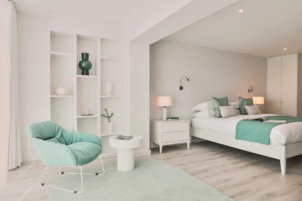 a white bedroom with a bed and a chair at St Moritz Hotel and Cowshed Spa in Polzeath