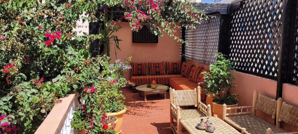 a patio with a couch and some flowers at Surf Riad Taghazout in Taghazout