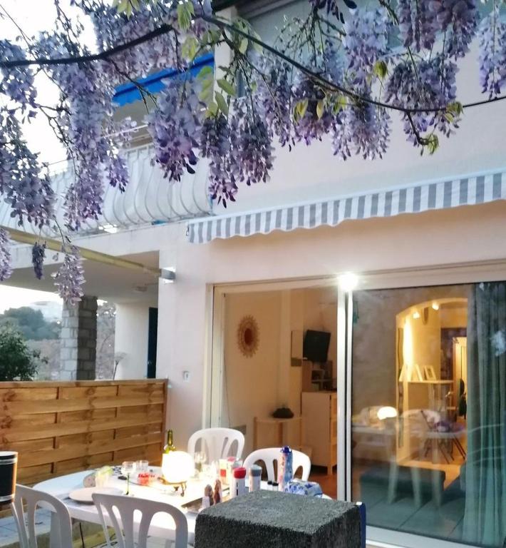 une terrasse avec une table, des chaises et des fleurs violettes dans l'établissement VERDON GRAN VALA 2 les pieds dans l'eau, à Martigues