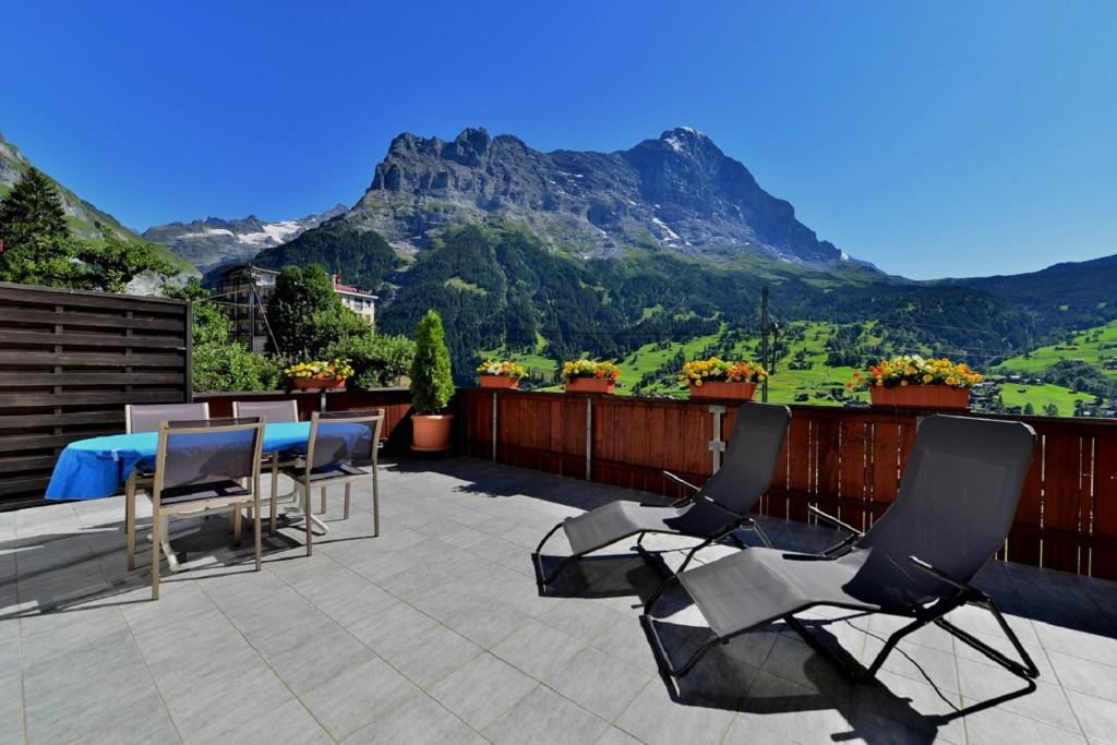 グリンデルワルトにあるFerienwohnung Alpenglühenの山の景色を望むパティオ(テーブル、椅子付)