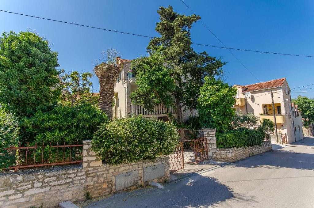 a house with a stone retaining wall and trees at Apartments KATA in Supetar