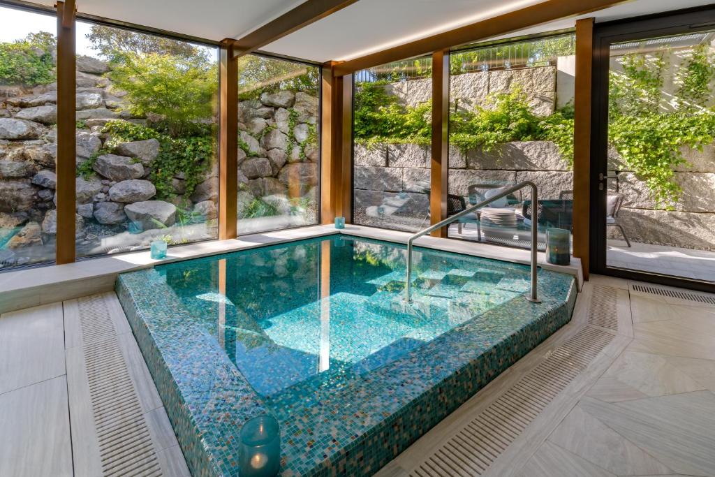 an indoor swimming pool with glass walls and a large window at FIVE Zurich - Luxury City Resort in Zürich