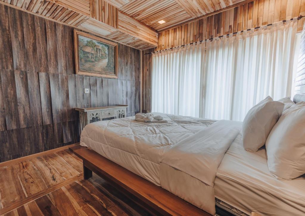 a bedroom with a bed with a wooden wall at Munduk Panorama in Munduk