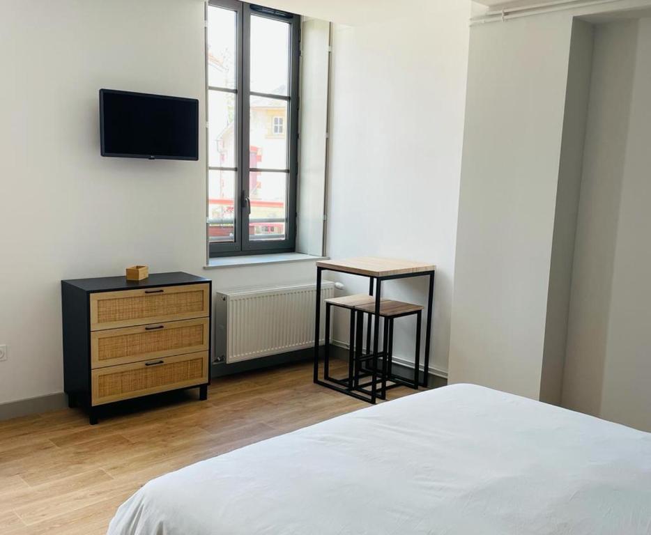 a bedroom with a bed and a desk and a tv at LE BON LABOUREUR in Moulins-Engilbert