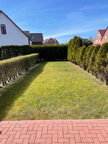 a brick walkway in a yard with a hedge at Sternschnuppe in Borkum
