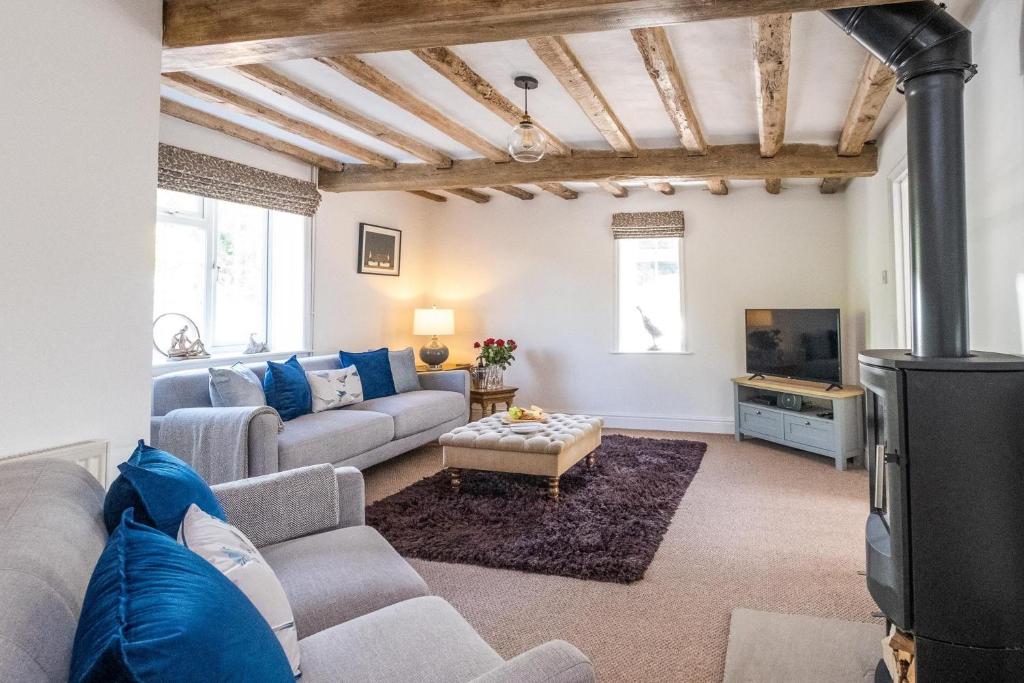 sala de estar con sofá y TV en Laurel Cottage - Aldeburgh Coastal Cottages, en Blyford