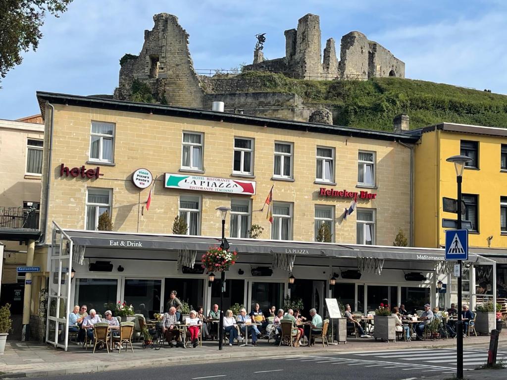 een groep mensen die buiten een gebouw met een kasteel zitten bij Hotel Restaurant La Piazza in Valkenburg