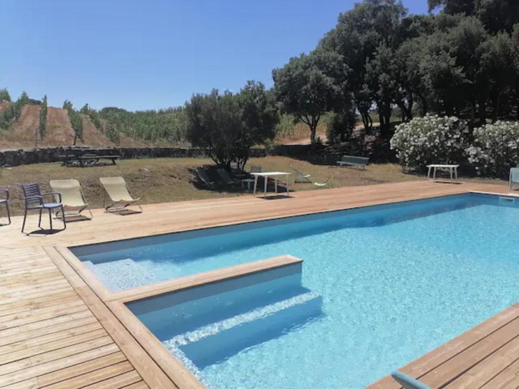 una gran piscina con terraza de madera junto a un patio en Gîtes Carbuccia en Corse avec piscine chauffée en Carbuccia