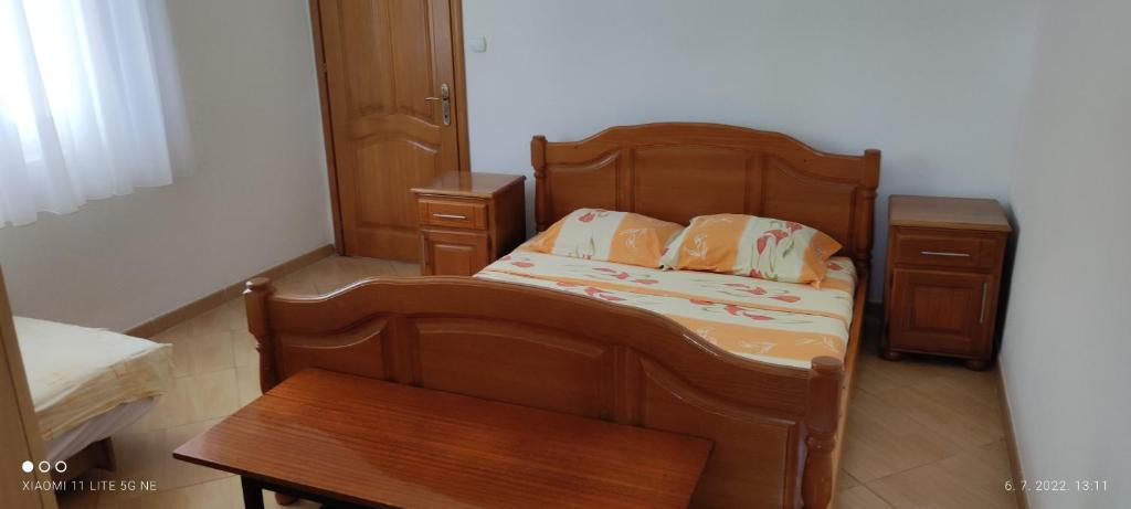 1 dormitorio con cama de madera y mesa en Apartman Bojovic Sutomore en Sutomore
