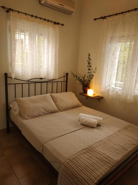a bed in a bedroom with two windows at Leodi Place in Kipséli