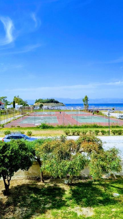 a view of a tennis court with trees and the ocean at Anna Garden Sidari in Sidari