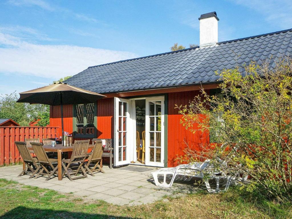 a red house with a patio with a table and chairs at 6 person holiday home in Nex in Snogebæk