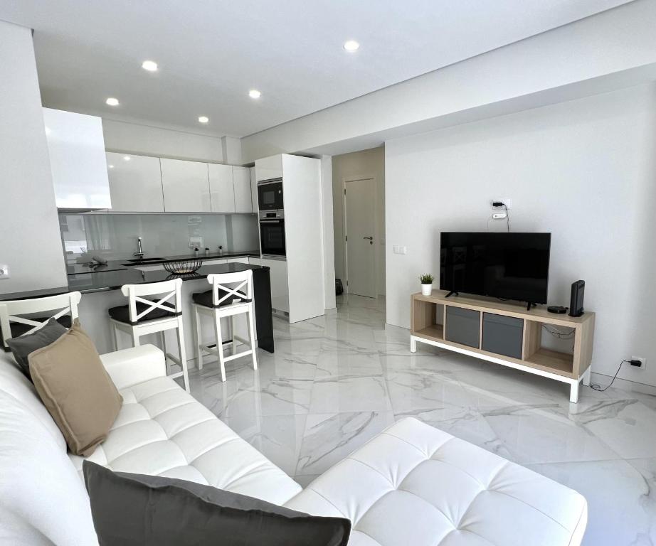 a living room with a white couch and a television at Aman - Near the beach by HD PROPERTIES in Cavacos