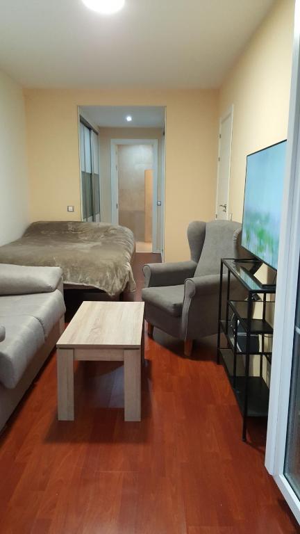 salon z łóżkiem, kanapą i telewizorem w obiekcie Suit piscina y terraza w mieście San Lorenzo de El Escorial