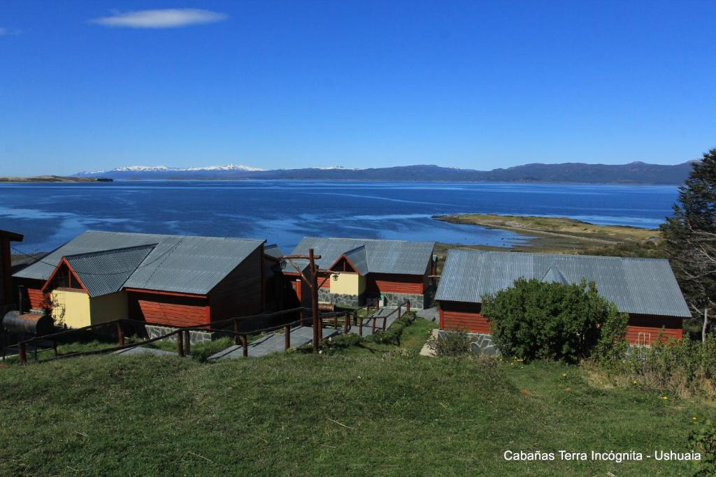 um grupo de cabanas ao lado de uma massa de água em Terra Incognita em Ushuaia