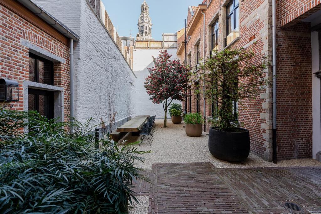 einen Innenhof mit einer Bank, Pflanzen und einem Turm in der Unterkunft BTFL Living Antwerp in Antwerpen