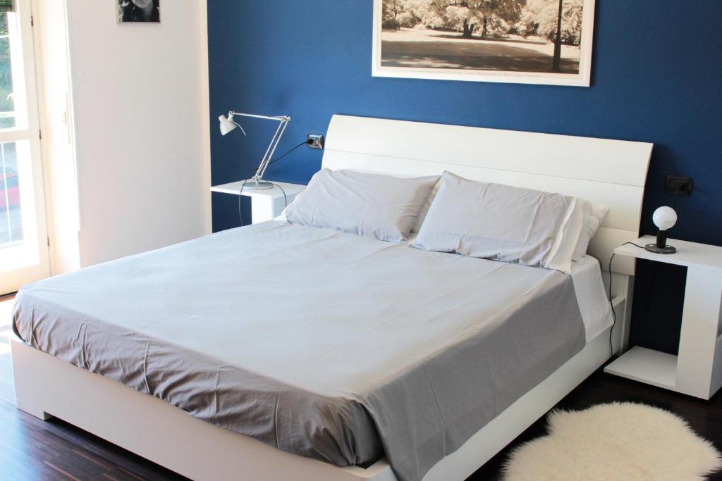 - une chambre avec un lit blanc et un mur bleu dans l'établissement Casa di Princi, à Brunate