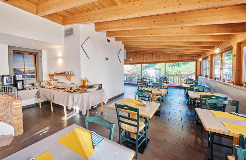 restauracja z drewnianymi sufitami, stołami i krzesłami w obiekcie Hotel Bed & Bike Ledro w mieście Molina di Ledro