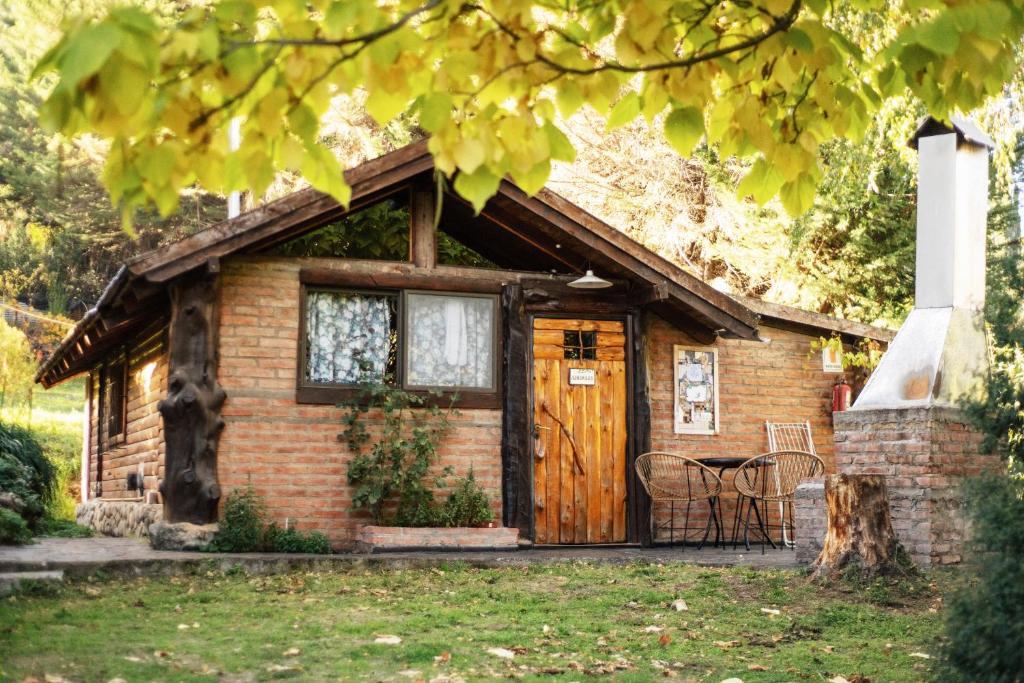 una piccola casa in mattoni con porta in legno di Cabañas del Faldeo Titos a El Bolsón