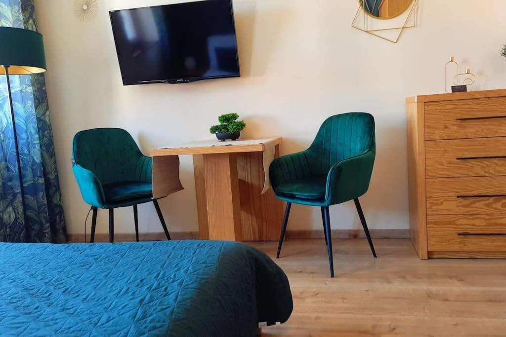a bedroom with two chairs and a table and a tv at APARTAMENTY TR 11 Apartament nr 3 in Olsztyn